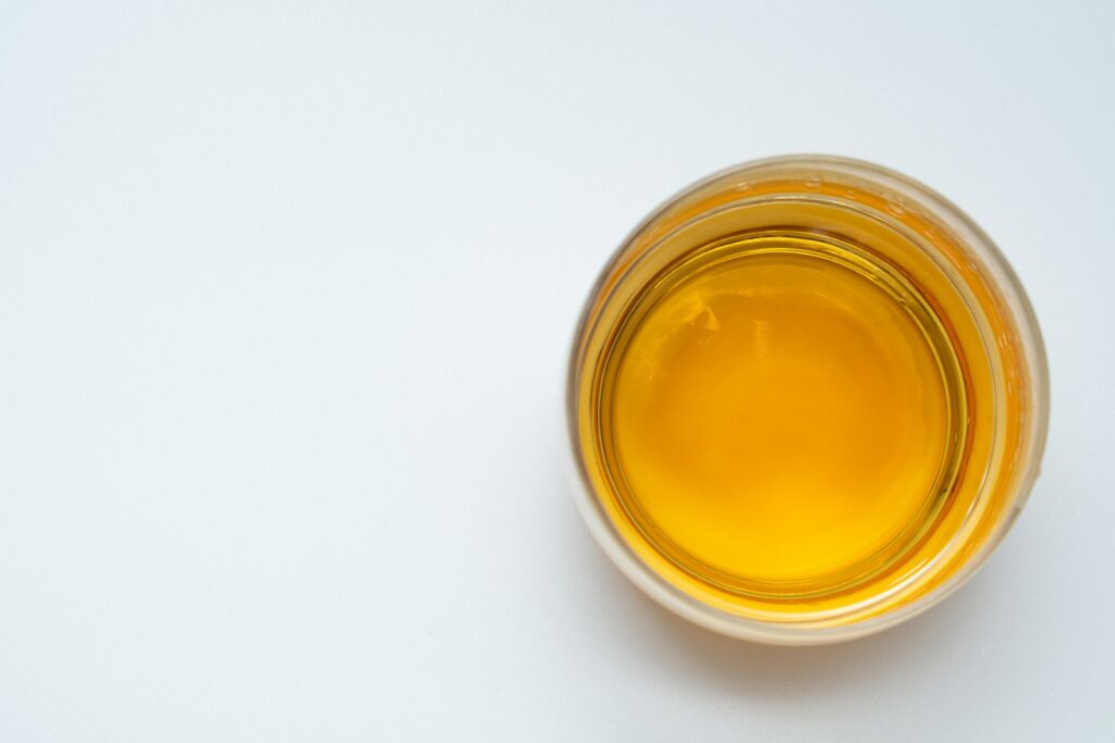 a glass filled with yellow liquid on top of a white table